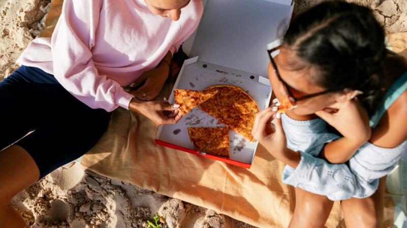people eating pizza on the beach