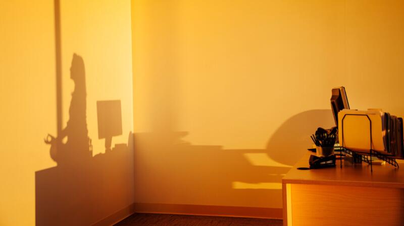 A shadow of a meditating person on a wall