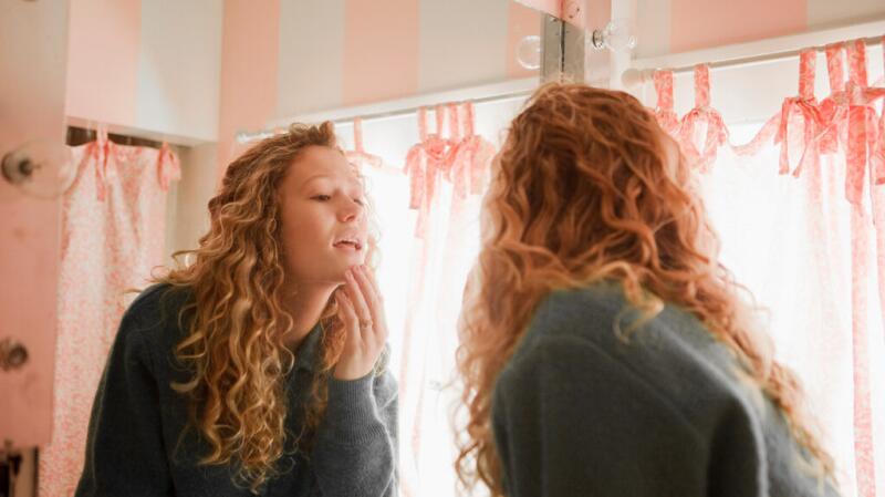 Young girl checking her skin in a mirror