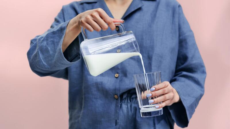 A person is pouring milk into a glass.