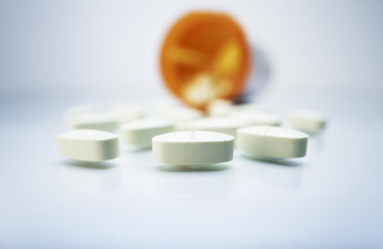 white oval pills spilling out of prescription bottle