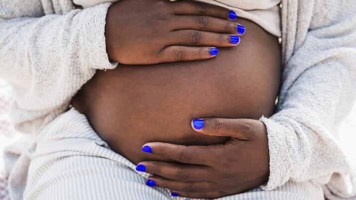 Close-up of Black pregnant person holding bare belly
