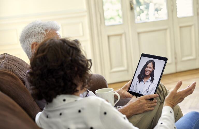 Senior couple video conferencing with doctor through digital tablet in living room