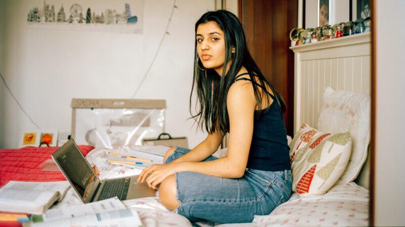 person sitting on a bed searching on a laptop