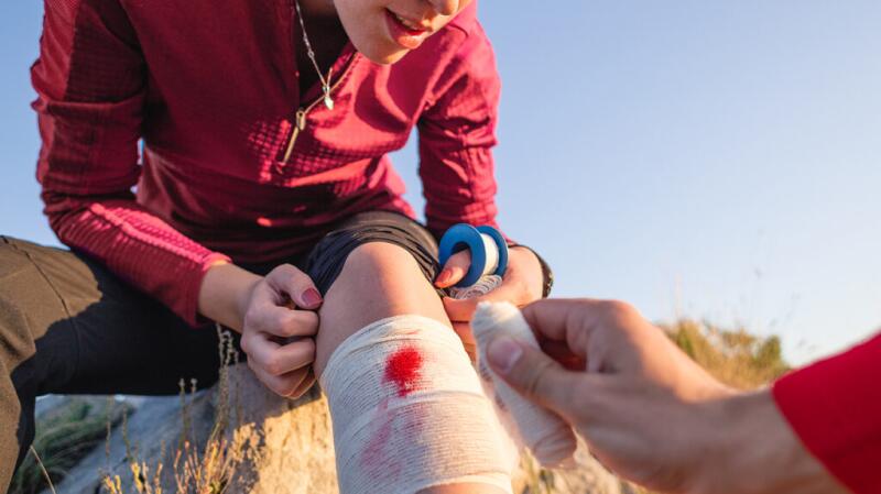 A person bandaging a wound on their leg