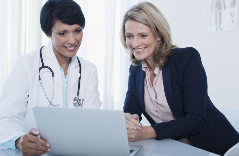 Doctor and patient using laptop in hospital office