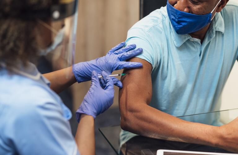 healthcare provider administering COVID-19 vaccine to man