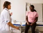 a woman wearing a pink shirt is talking to a doctor