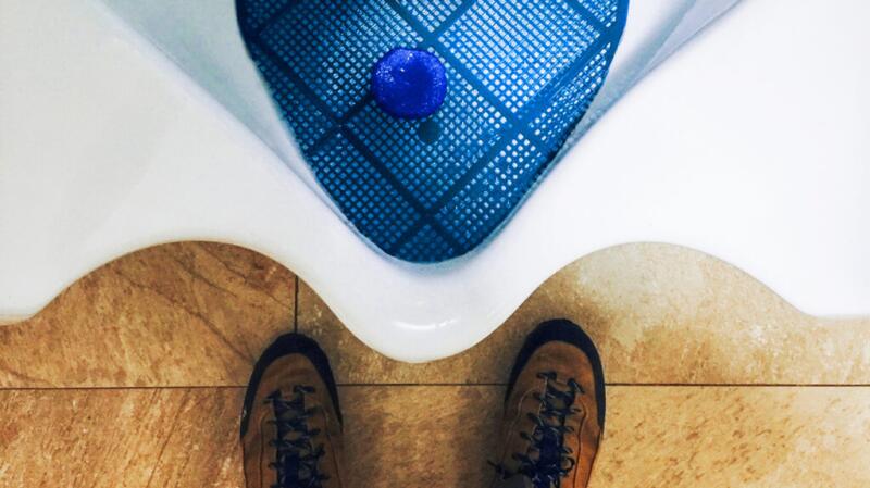 Image of feet in front of a urinal