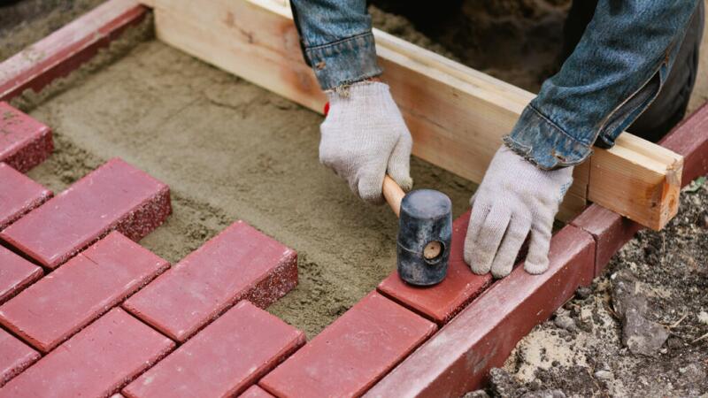 There is a closeup of a person hammering bricks.