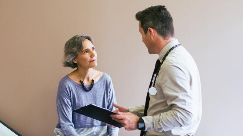 an older patient is talking to a doctor in a clinic