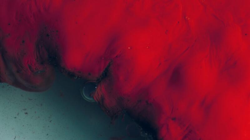 There is a close-up photo of red blood over a dark green background.