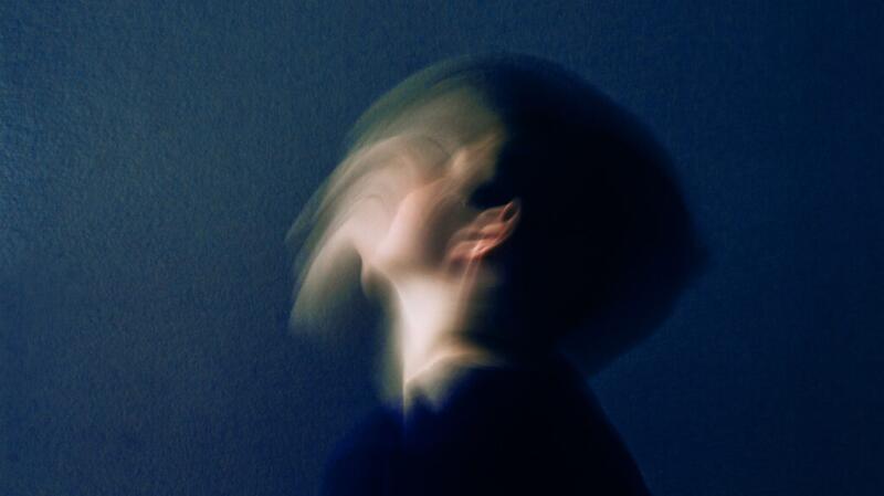 A blurred long-exposure image of someone's head tilting backward.
