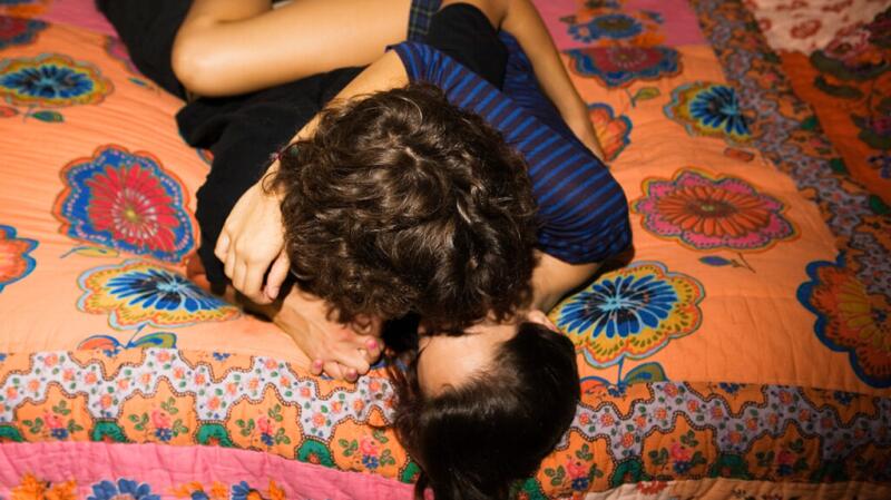 A couple lying on a bed, kissing
