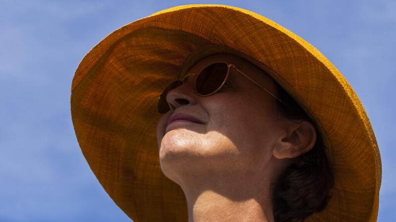 Woman wearing a hat and sunglasses on a sunny day.