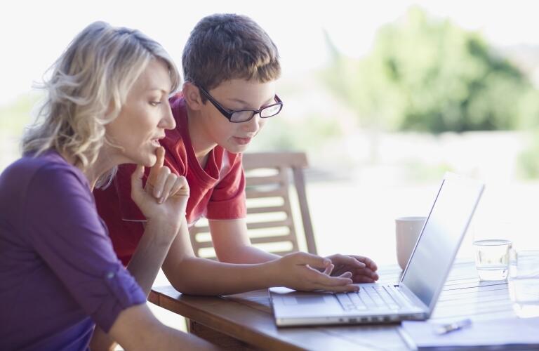 Mother and teenage son looking at laptop together