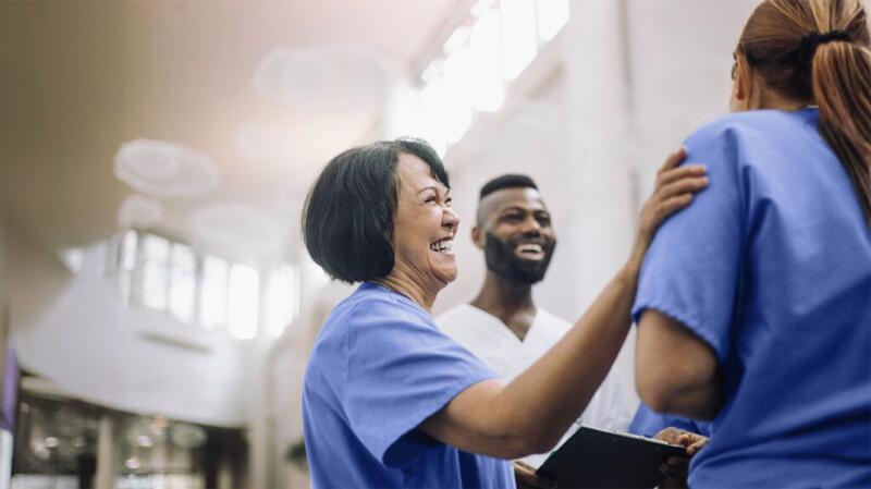 Physicians wearing blue and white scrubs laugh together.