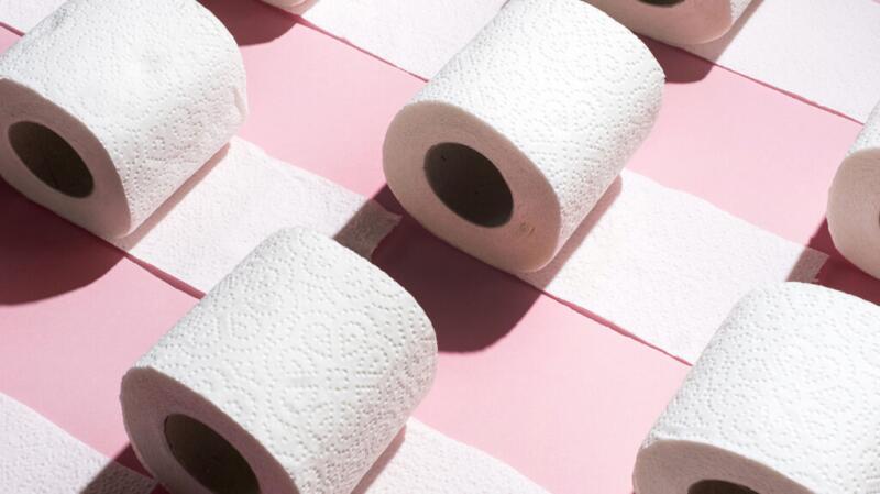 There are rolls of toilet paper against a pink background.