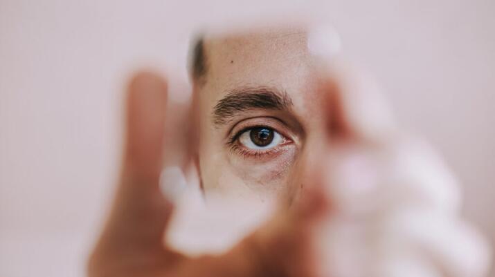 Person looking at their eye in the mirror