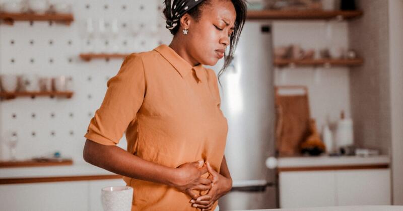 female with stomach pain holding hands against her stomach