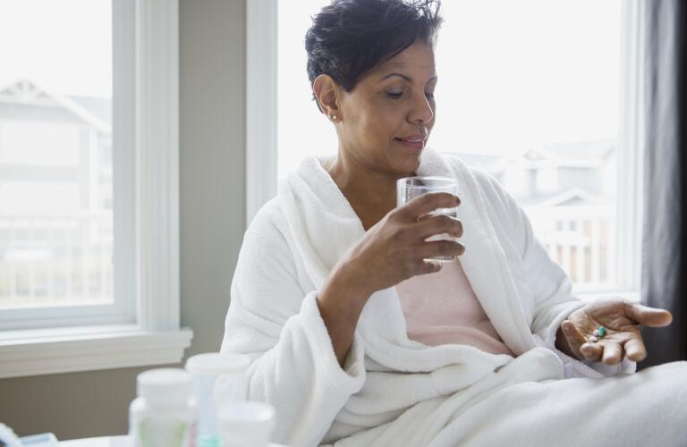 woman in bathrobe taking vitamins or medication