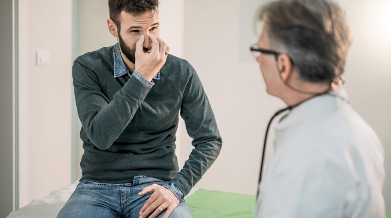 adult male patient describing his nasal problem to a physician