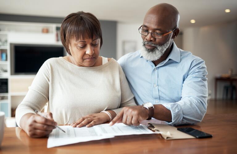 Senior African American couple reviewing paperwork at home