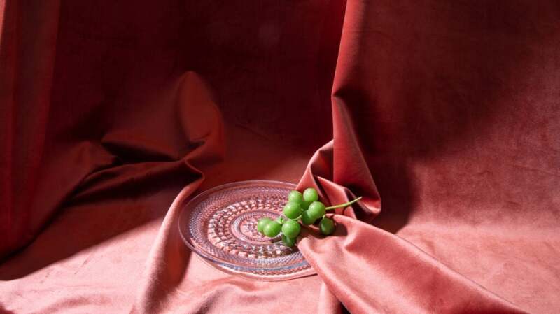 Green grapes on a glass plate against a red background