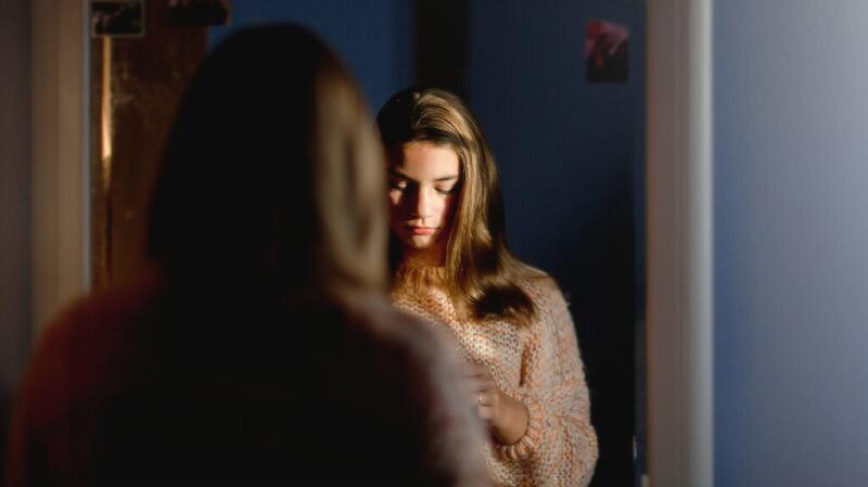A young woman is standing in front of a mirror.