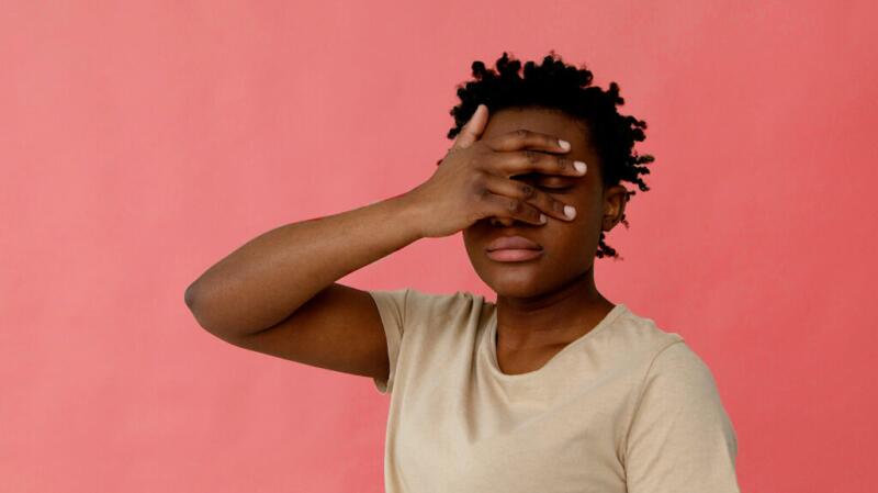 young person covering eye with hand but with space to see