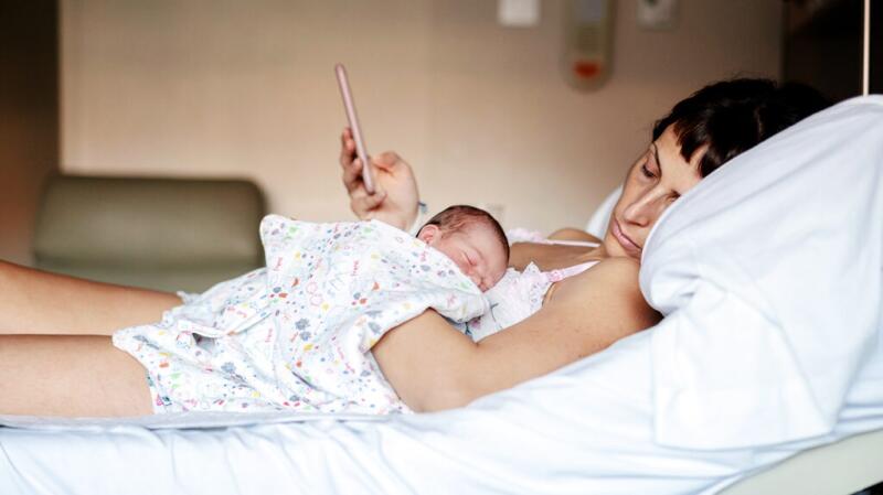 Mother in hospital bed with newborn baby lying on chest