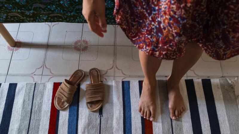 A person stands on the edge of a towel with bare feet. 