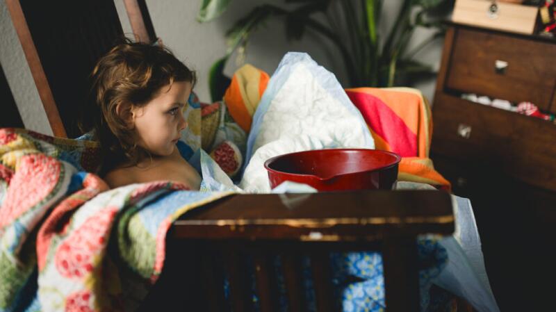 child with sick bowl, looking unwell