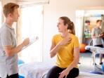 woman talking about her shoulder with a physical therapist in his office 