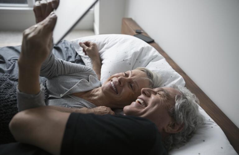 Senior Caucasian couple taking selfie together in bed