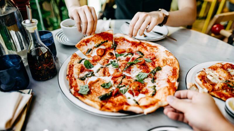 Close up of hands grabbing pieces of pizza