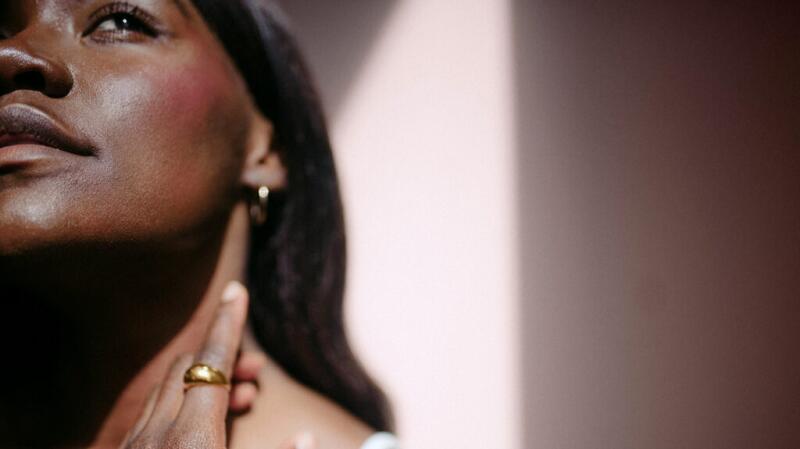 black woman gazing up with her hand near her jawline