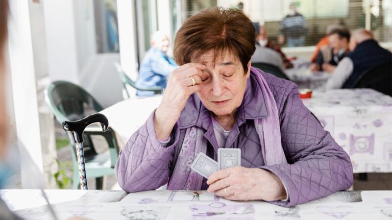Female playing cards and touching her forehead