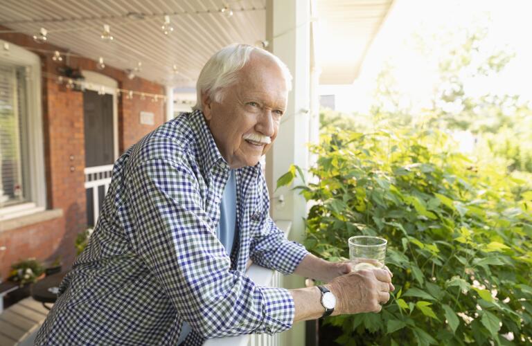 Senior Caucasian man drinking water or lemonade on front porch