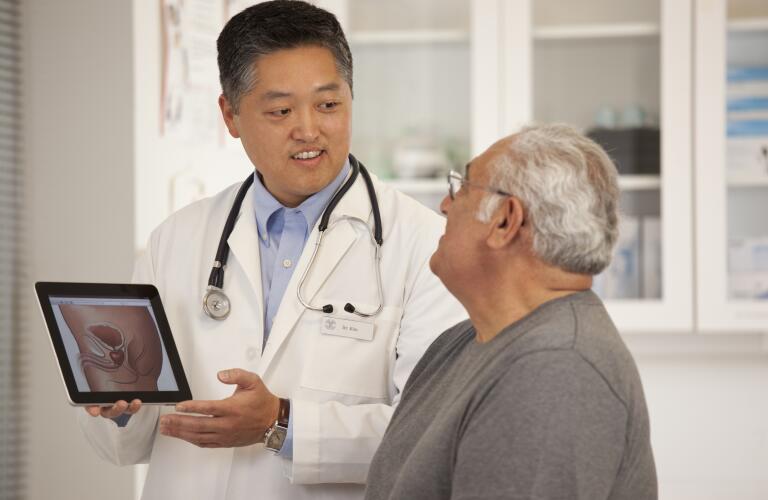 doctor using digital tablet to discuss prostate anatomy with patient